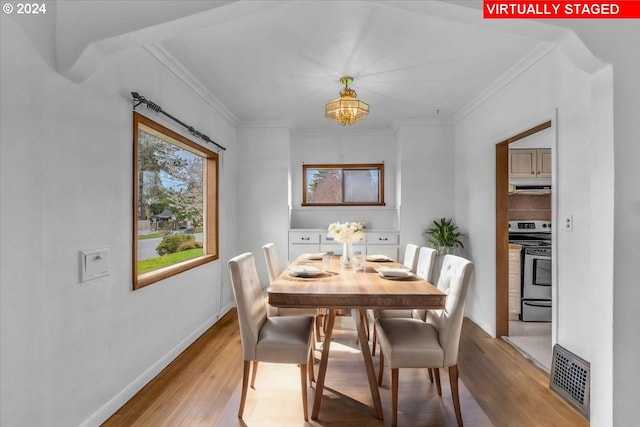 dining area featuring ornamental molding and light hardwood / wood-style flooring