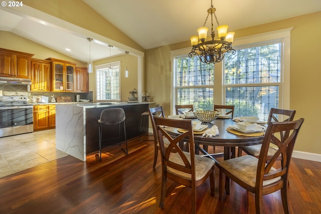 dining space featuring lofted ceiling, a healthy amount of sunlight, light wood-type flooring, and a chandelier