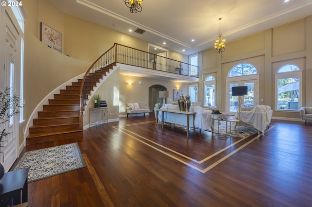 living room with a chandelier, a towering ceiling, dark wood-type flooring, and ornamental molding