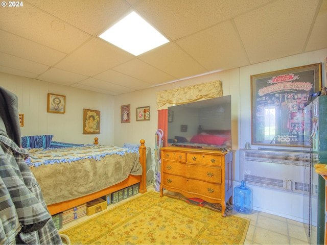 tiled bedroom featuring radiator and a drop ceiling