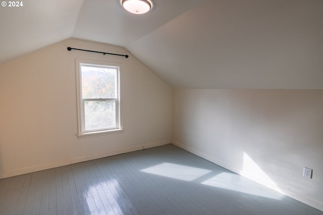 additional living space with hardwood / wood-style floors and vaulted ceiling