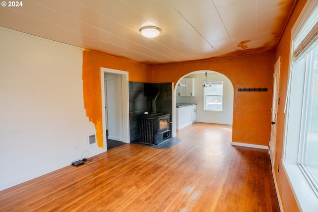 410 N Mountain Blvd, Mount Vernon, OR 97865 - unfurnished living room with baseboards, arched walkways, wood finished floors, and a wood stove