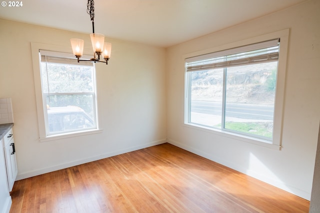 unfurnished dining area featuring a notable chandelier and light wood-type flooring