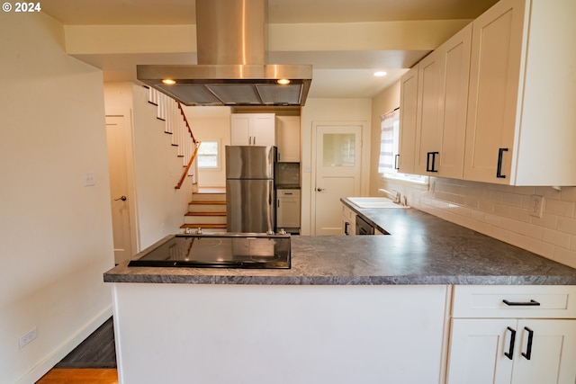 kitchen featuring island exhaust hood, stainless steel refrigerator, kitchen peninsula, and white cabinets