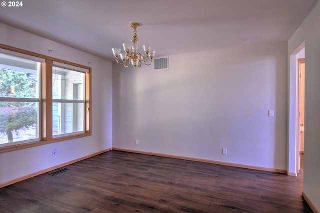 unfurnished room featuring a notable chandelier and dark hardwood / wood-style flooring