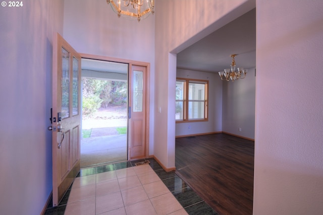 entryway with an inviting chandelier, a towering ceiling, and wood-type flooring