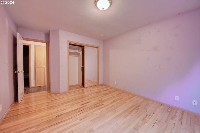 unfurnished bedroom featuring a textured ceiling, light wood-type flooring, and a closet