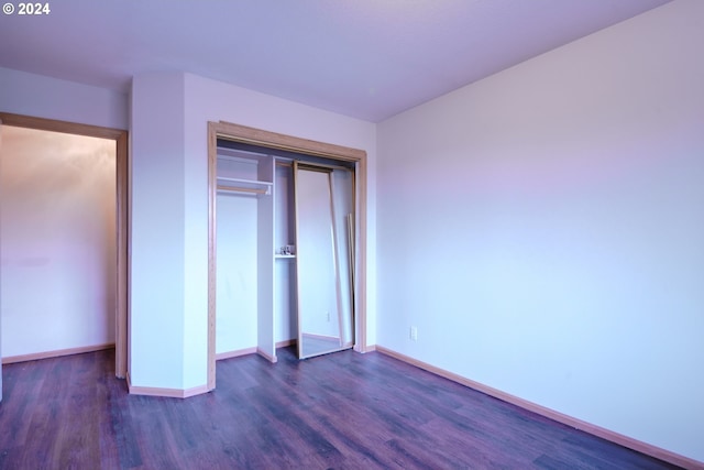 unfurnished bedroom with a closet and dark wood-type flooring