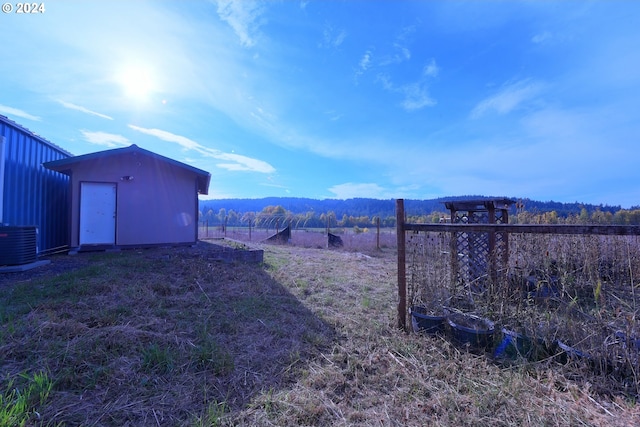 view of yard featuring a rural view, a shed, a mountain view, and cooling unit