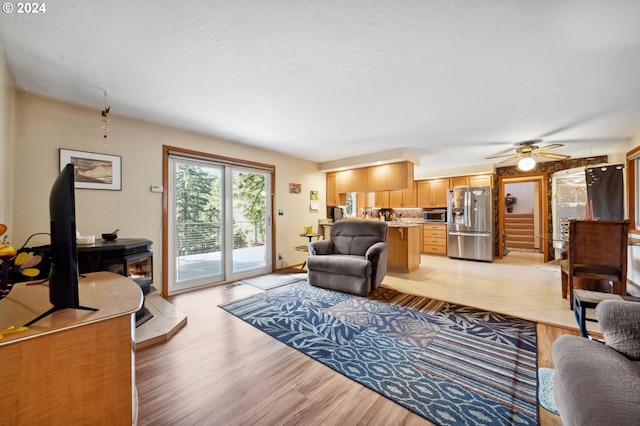 tiled living room with ceiling fan and a wood stove