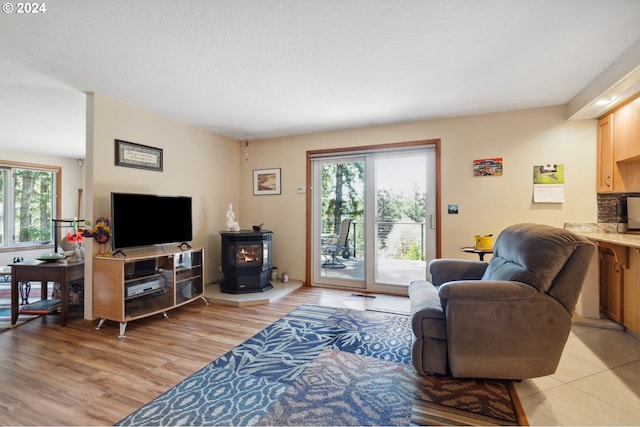 living room with plenty of natural light, a wood stove, and light hardwood / wood-style flooring