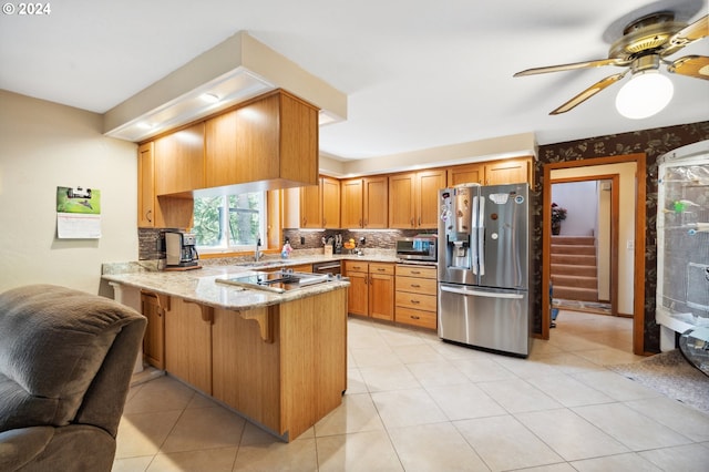 kitchen featuring kitchen peninsula, ceiling fan, light tile floors, backsplash, and stainless steel appliances