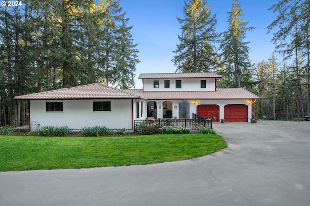 mediterranean / spanish-style house featuring covered porch, a front yard, and a garage