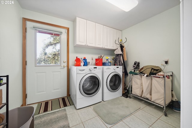 washroom featuring light tile floors, cabinets, and washer and clothes dryer