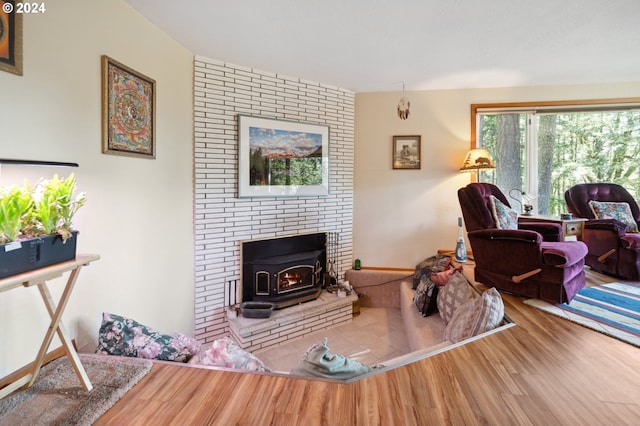 living room with brick wall, a brick fireplace, and wood-type flooring