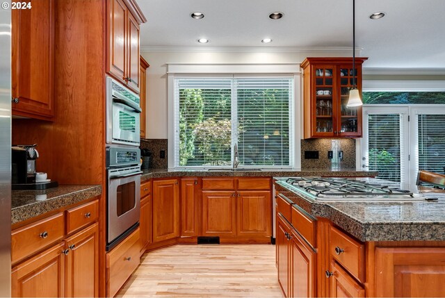 kitchen with tasteful backsplash, crown molding, pendant lighting, and light hardwood / wood-style flooring