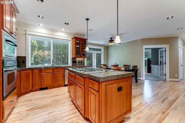 kitchen featuring decorative backsplash, appliances with stainless steel finishes, a kitchen island, and light hardwood / wood-style flooring