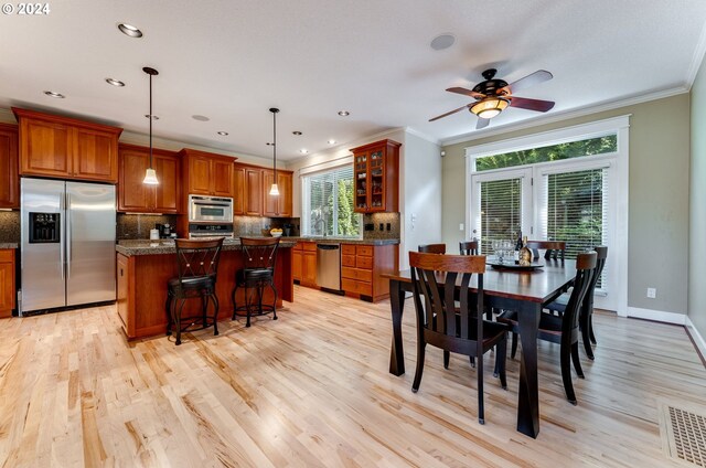 dining space with ceiling fan, ornamental molding, sink, and light wood-type flooring