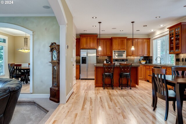 kitchen featuring a breakfast bar, dark stone countertops, hanging light fixtures, stainless steel appliances, and a kitchen island