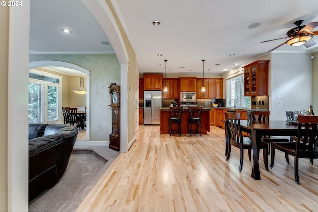 dining area featuring crown molding, plenty of natural light, sink, and light wood-type flooring