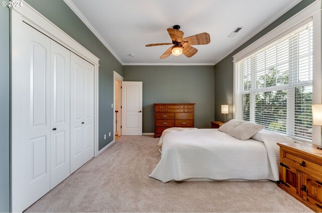 carpeted bedroom featuring crown molding, ceiling fan, and a closet