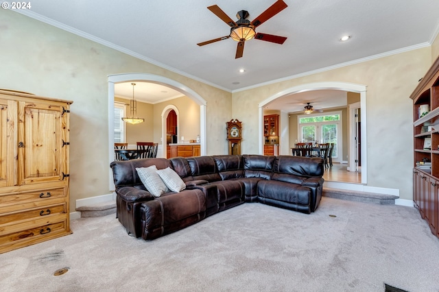 carpeted living room featuring crown molding and ceiling fan