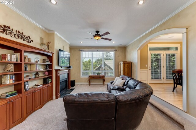 carpeted living room featuring ornamental molding, ceiling fan, and a textured ceiling