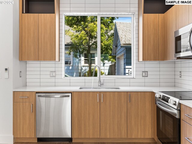 kitchen with decorative backsplash, appliances with stainless steel finishes, and sink