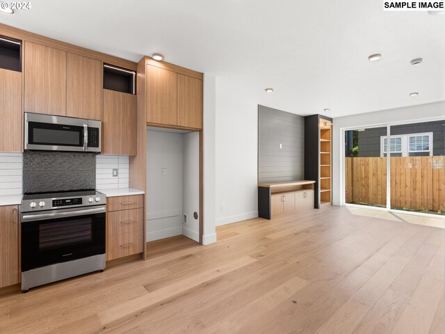 kitchen featuring appliances with stainless steel finishes, light hardwood / wood-style flooring, and decorative backsplash