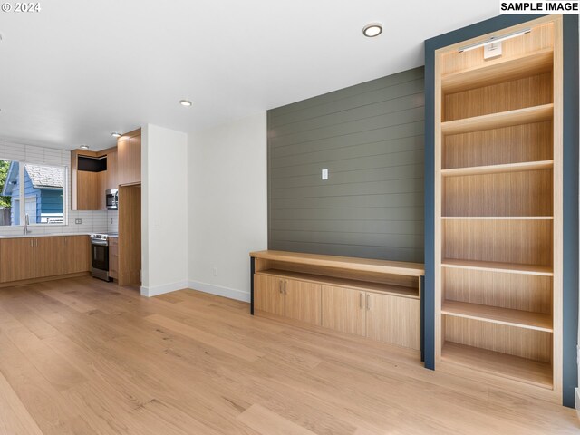 unfurnished living room with sink and light hardwood / wood-style flooring