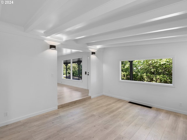 spare room featuring beamed ceiling and light hardwood / wood-style floors