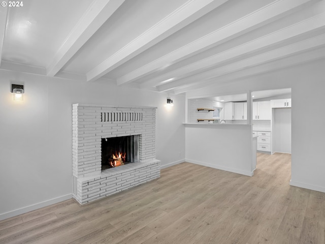 unfurnished living room featuring a fireplace, beamed ceiling, and light hardwood / wood-style floors