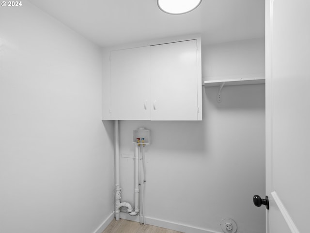 laundry area with cabinets, hookup for a washing machine, and light wood-type flooring