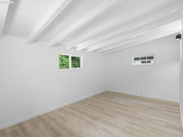 unfurnished room with light wood-type flooring and lofted ceiling with beams