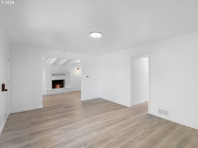 unfurnished living room with beamed ceiling, light hardwood / wood-style flooring, and a fireplace