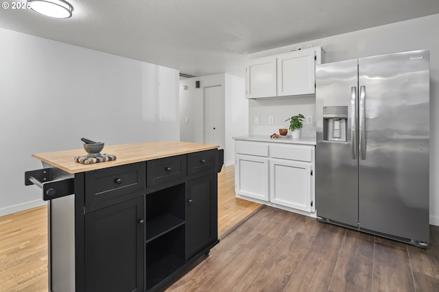 kitchen featuring wood-type flooring, a center island, stainless steel fridge with ice dispenser, and white cabinets