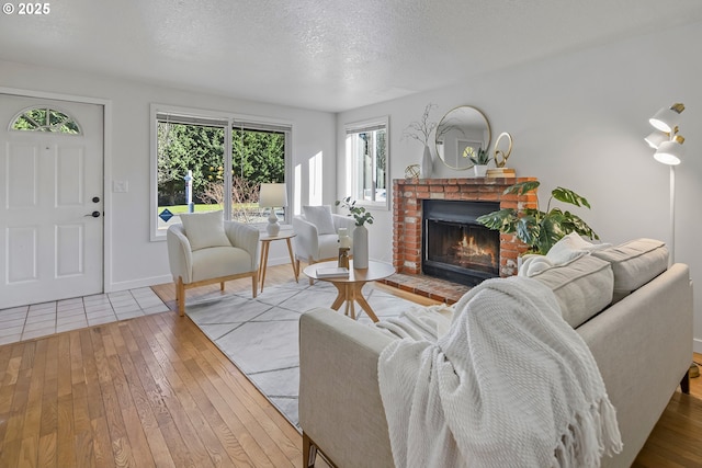 living room with a textured ceiling, a fireplace, and light hardwood / wood-style flooring