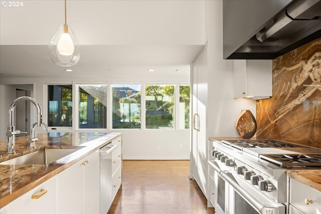 kitchen with pendant lighting, sink, white cabinets, stainless steel appliances, and wall chimney exhaust hood