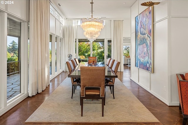 dining room featuring a healthy amount of sunlight, dark parquet flooring, and a chandelier