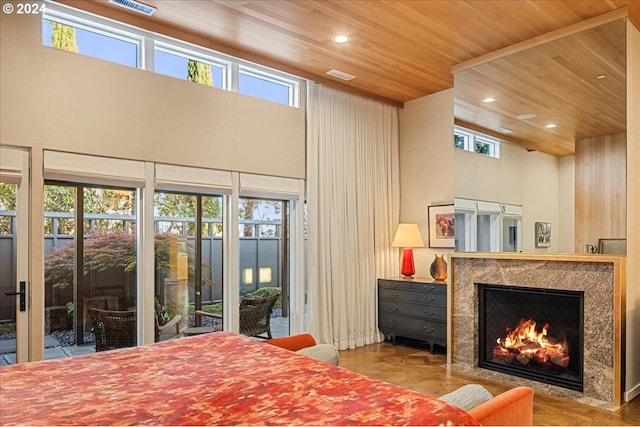 bedroom with a towering ceiling, wooden ceiling, a high end fireplace, and access to outside