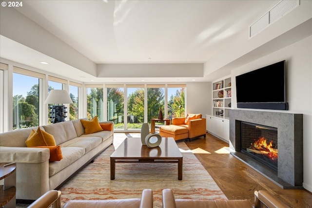 living room featuring a wealth of natural light, parquet floors, built in features, and a fireplace