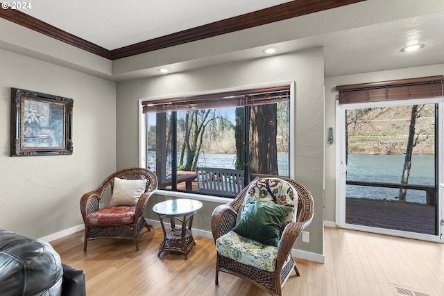 living area with crown molding and light hardwood / wood-style flooring