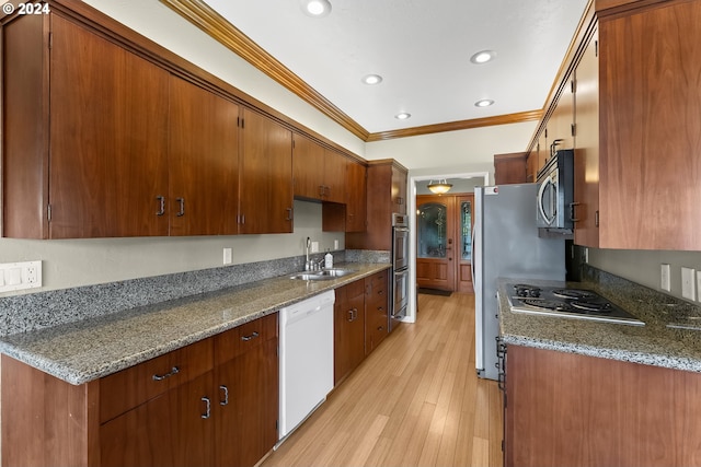 kitchen with ornamental molding, stainless steel appliances, sink, and dark stone countertops