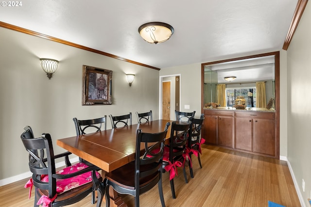 dining space with crown molding and light hardwood / wood-style floors