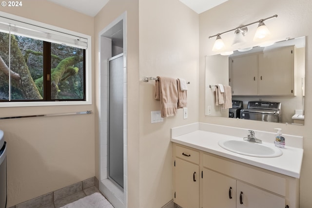 bathroom with vanity, tile patterned flooring, washing machine and dryer, and walk in shower