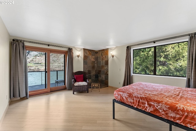 bedroom featuring multiple windows, access to outside, and light hardwood / wood-style floors