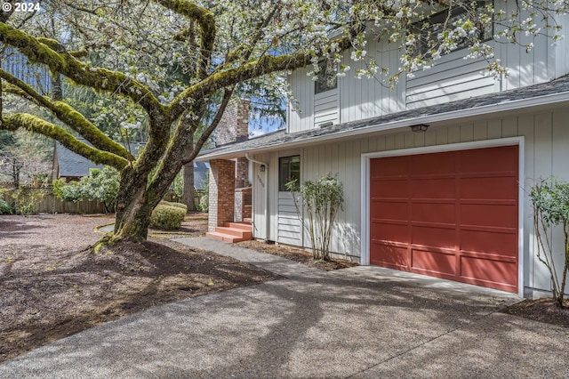 view of front of property with concrete driveway, a shingled roof, and a chimney