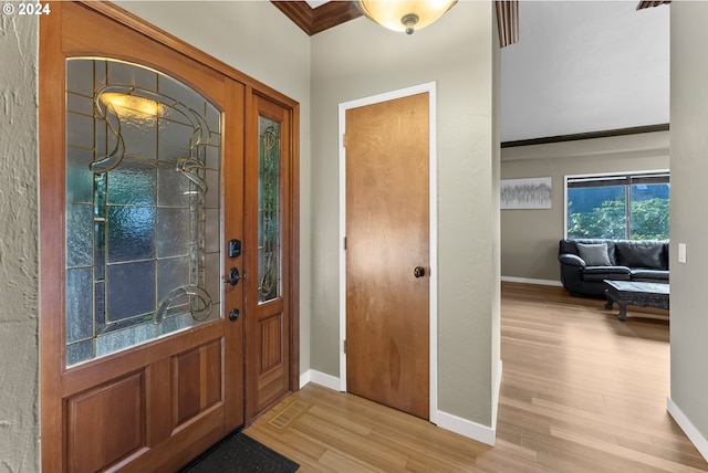 entryway featuring ornamental molding and light hardwood / wood-style floors