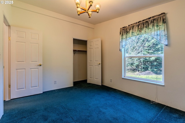 unfurnished bedroom with a closet, dark carpet, and a notable chandelier