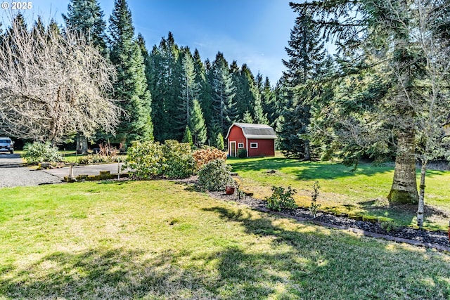 view of yard featuring an outbuilding, a view of trees, and a barn